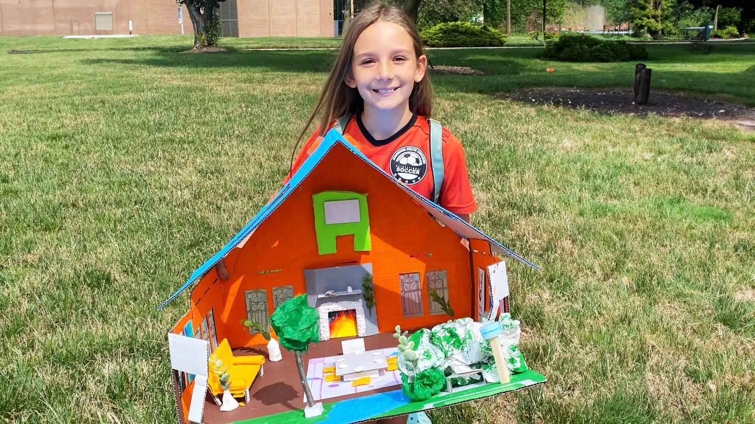 Child proudly holding a finished sewing craft, smiling