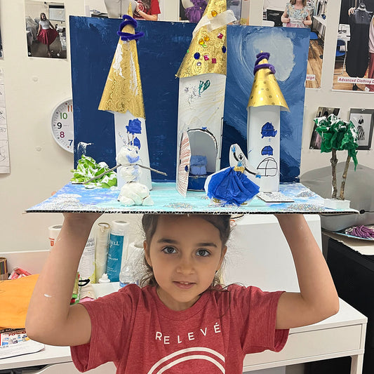 Student proudly holding a 3D castle model created in our Art Adventure design and art class for ages 6–8.